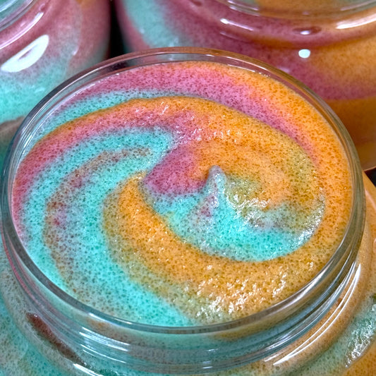 Colorful swirled sugar scrub in a plastic jar with a blurred background