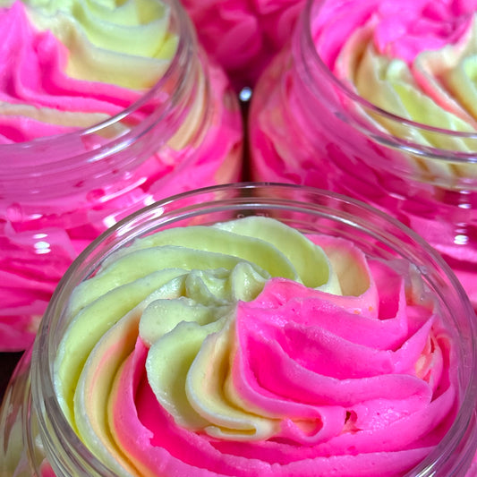 Close-up of pink and yellow layered whipped soap in clear containers.