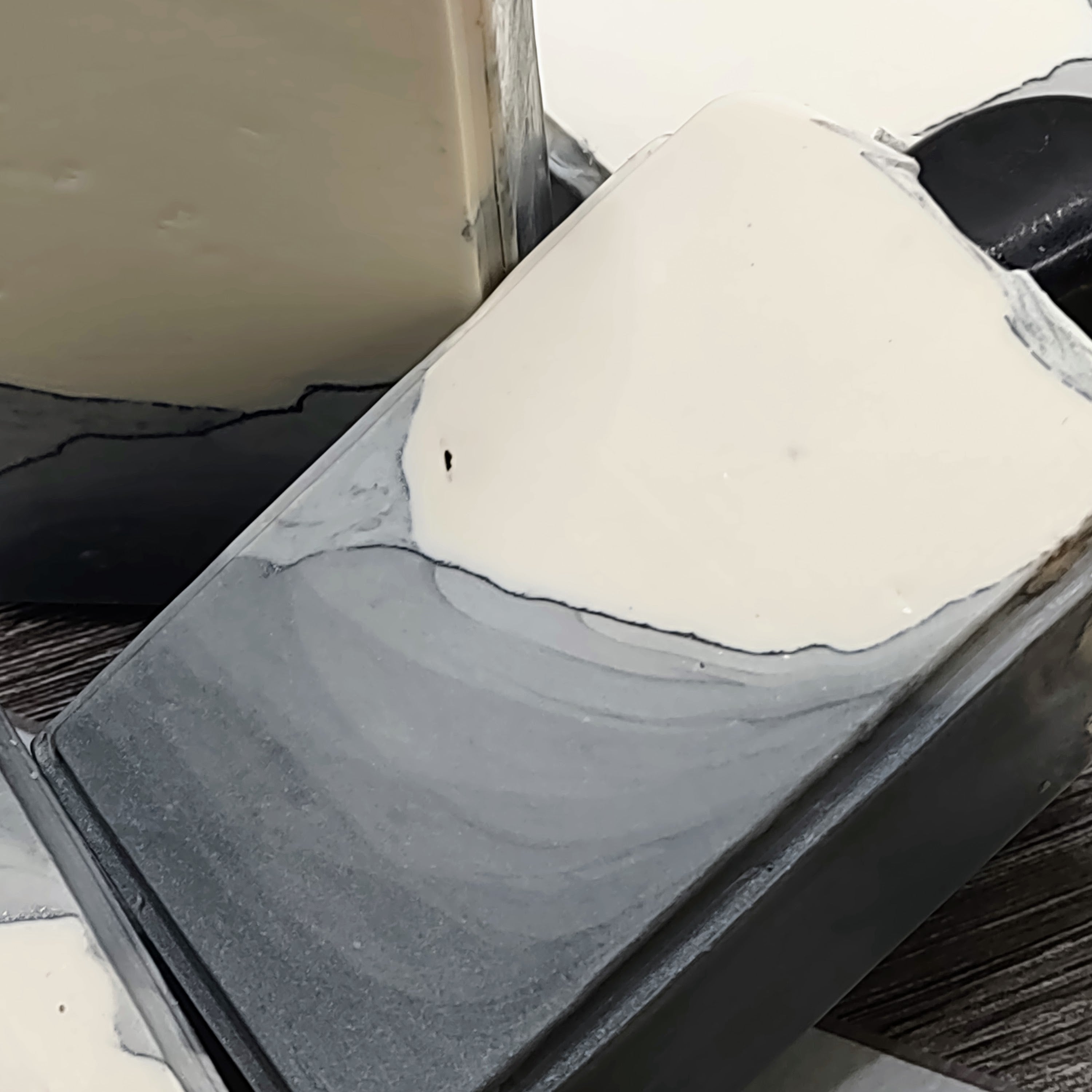 A gray and white bar of soap with an obsidian stone embedded on top. 