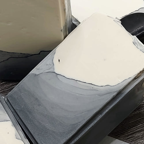 A gray and white bar of soap with an obsidian stone embedded on top. 