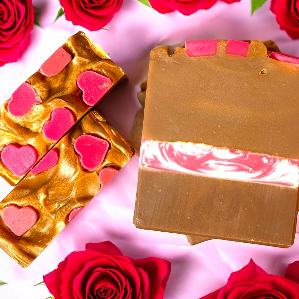 A bar of soap with a strawberries and cream fragrance, topped with pink hearts on a caramel colored swirl, displayed alongside red roses.