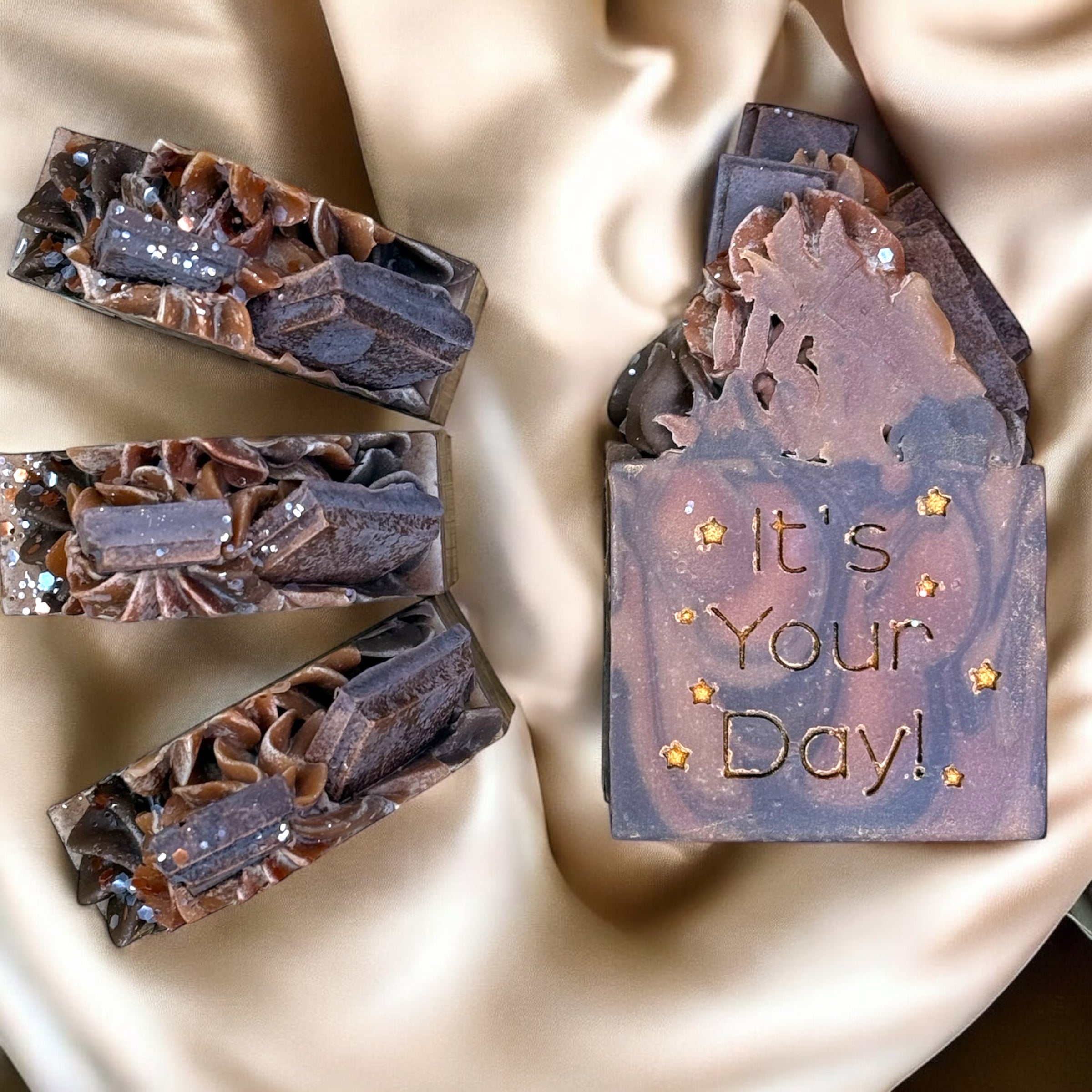 A bar of soap with a fudge brownie design, topped with mini chocolate bars, and the text 'It's Your Day!' stamped on the surface.