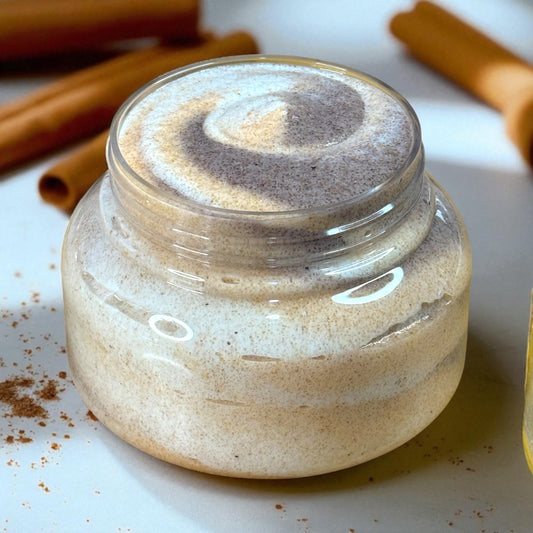Jar of cinnamon sugar scented sugar scrub in shades of brown and gold with cinnamon sticks in the background
